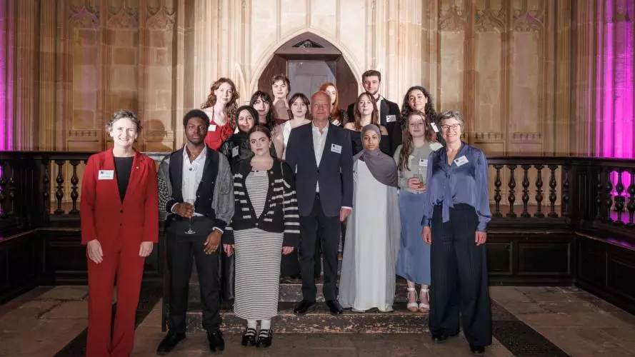 Group portrait taken in the Divinity School, Oxford. The Vice-Chancellor of Oxford stands on the far left wearing a red suit, and the Chancellor stands at the centre in a dark suit. At the right is the Director of the Astrophoria Foundation Year