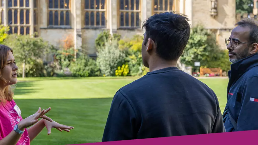 Photo of an Oxford University student ambassador talking to a prospective applicant and parent on a sunny college lawn