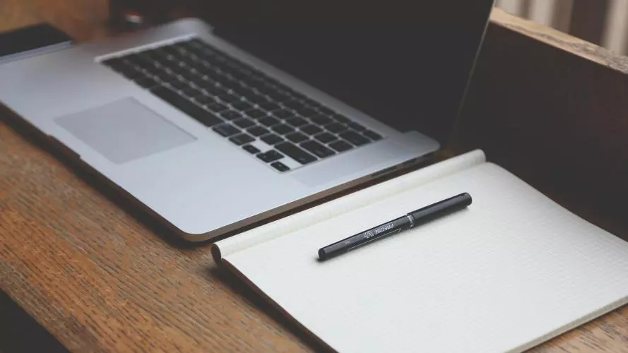 Laptop, notepad and pen on a desk