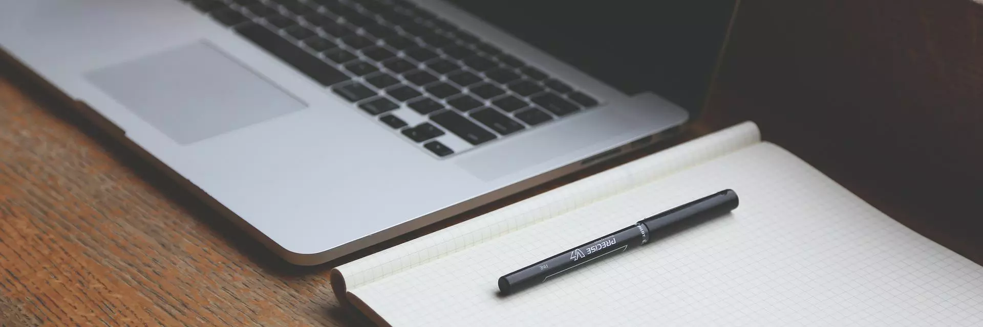Laptop, notepad and pen on a desk