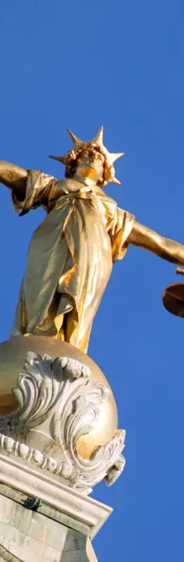A picture of Lady Justice, a gold figure with arms outstretched holding a sword in one hand and scales in the other, against a clear blue sky